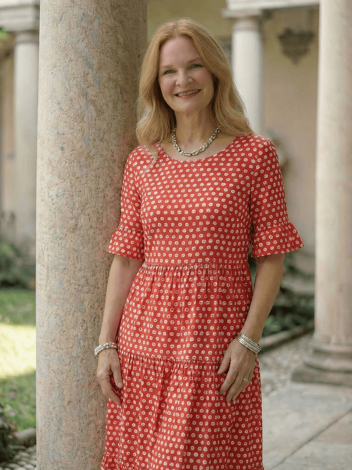 Emma & Rose Cape Town Arlo™ Dot Tiered Midi Dress shown hanging with floral accents and flowing fabric design.