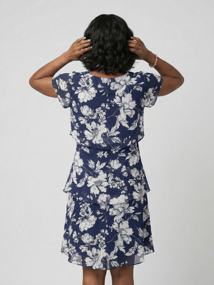 Thea™ floral knee-length dress by Emma & Rose Cape Town, showcasing a flowy fabric with vibrant floral patterns and a fitted waist.