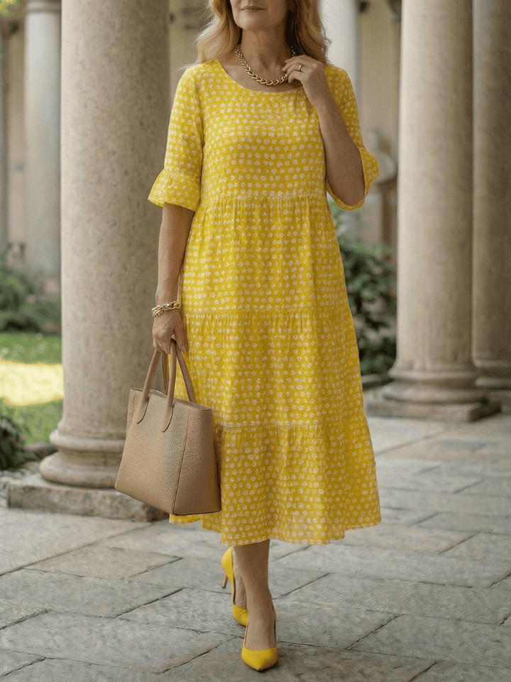 Emma & Rose Cape Town Arlo™ Dot Tiered Midi Dress displayed on a hanger with floral background.
