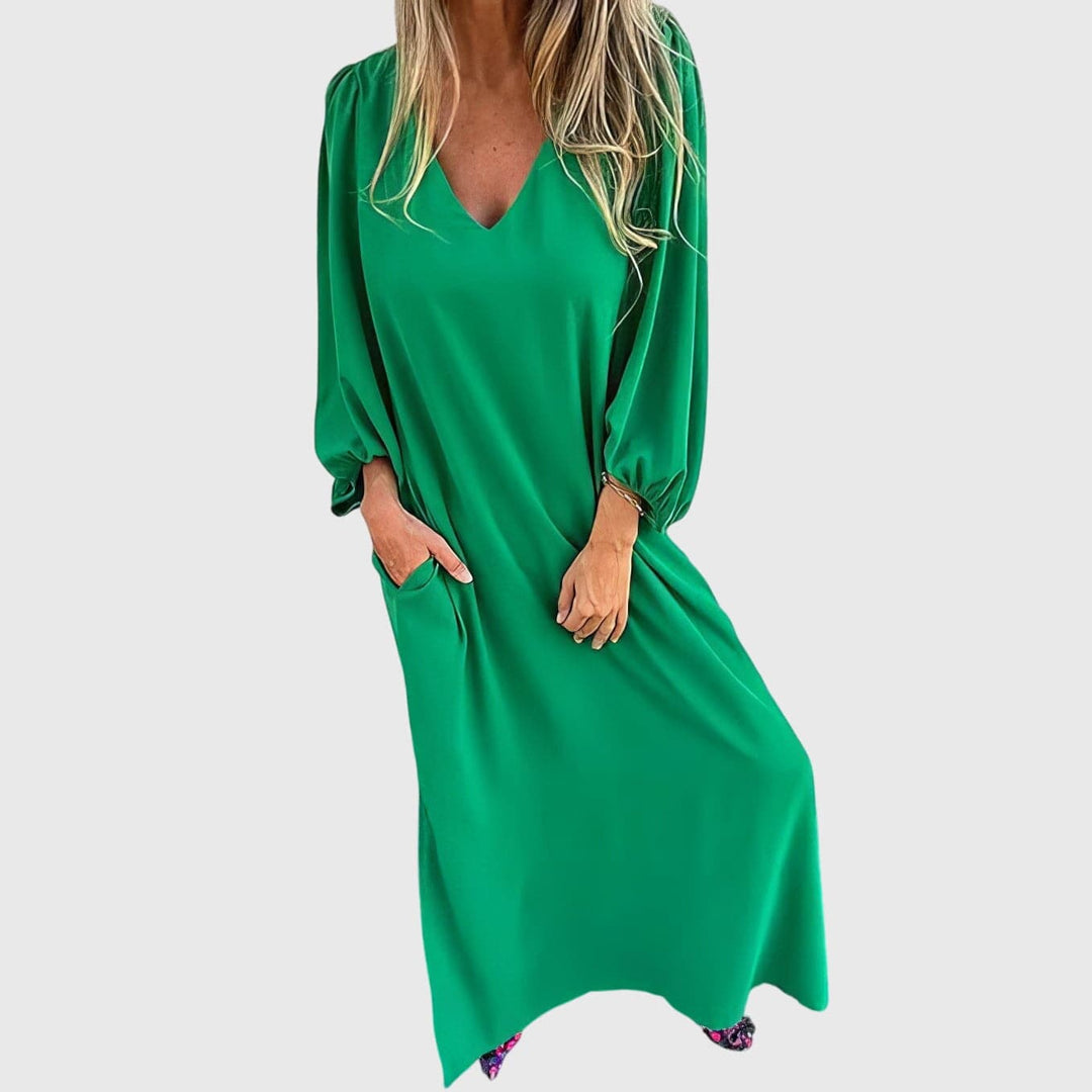 Emma & Rose Cape Town Carol™ long boho dress with pockets, flowing fabric, and bohemian style, shown hanging on a wooden hanger.