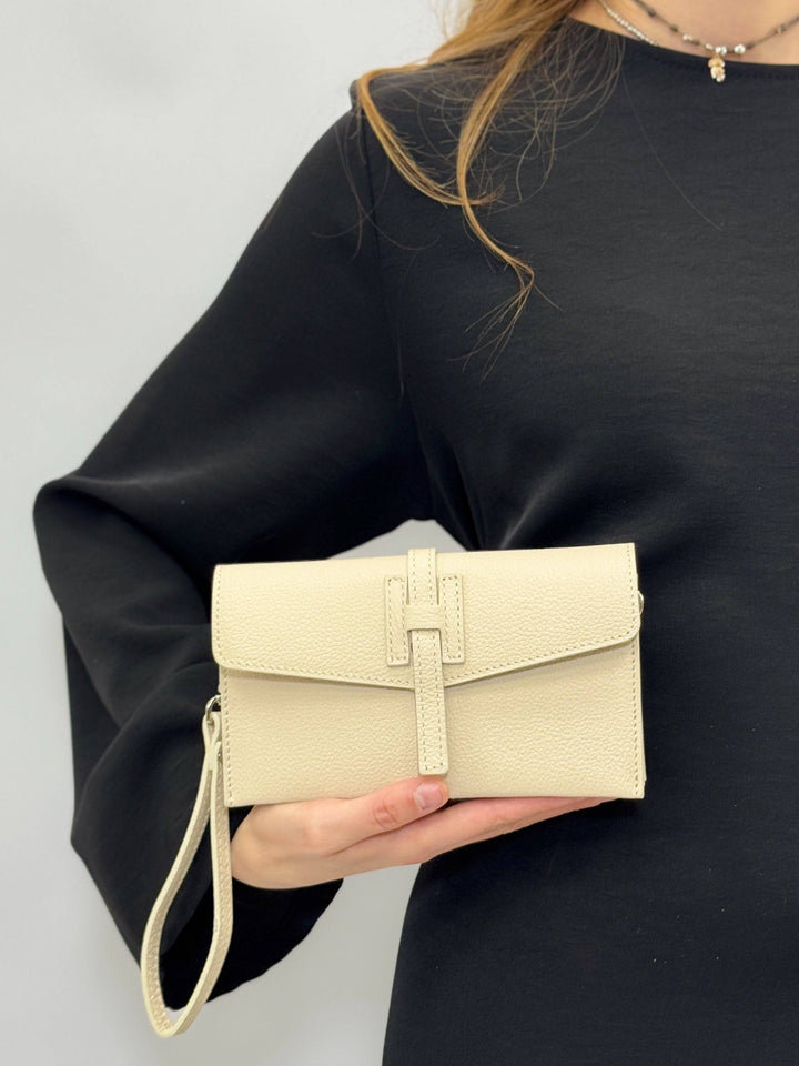 Emma & Rose Cape Town Yael™ leather clutch bag strap attached to a black clutch bag with gold hardware.