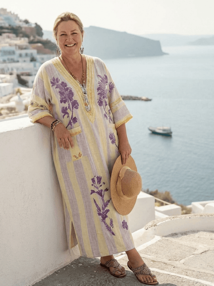 A woman wearing the Aurelia™ striped floral maxi dress by Emma & Rose Cape Town, standing outdoors in a sunny setting.