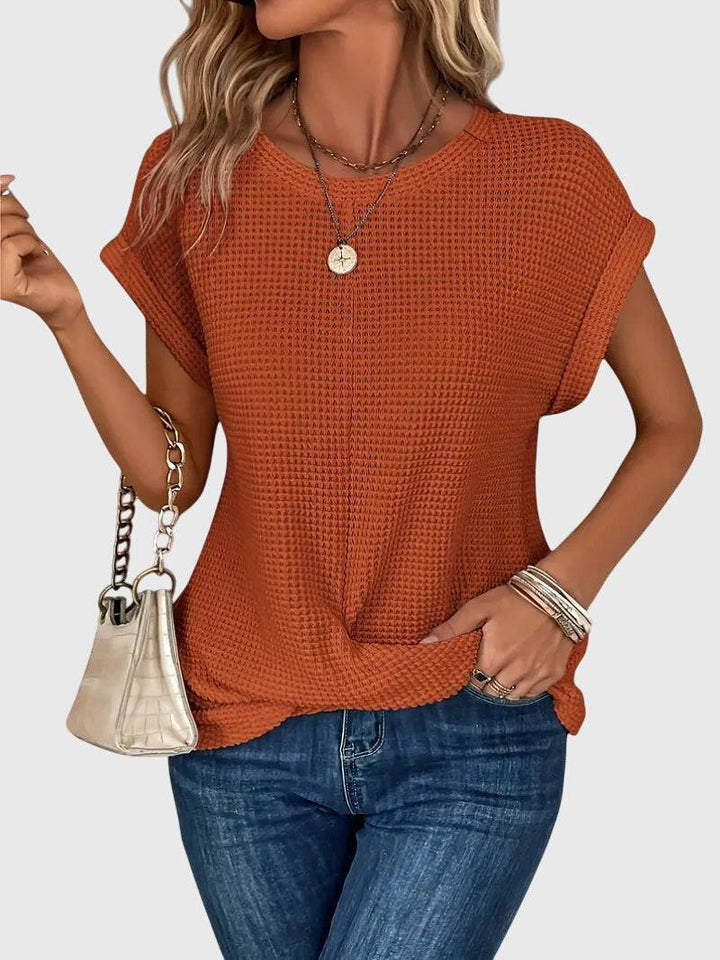 Elegant Emma & Rose Cape Town Isa™ blouse with a crew neck, displayed on a hanger with soft fabric details visible.