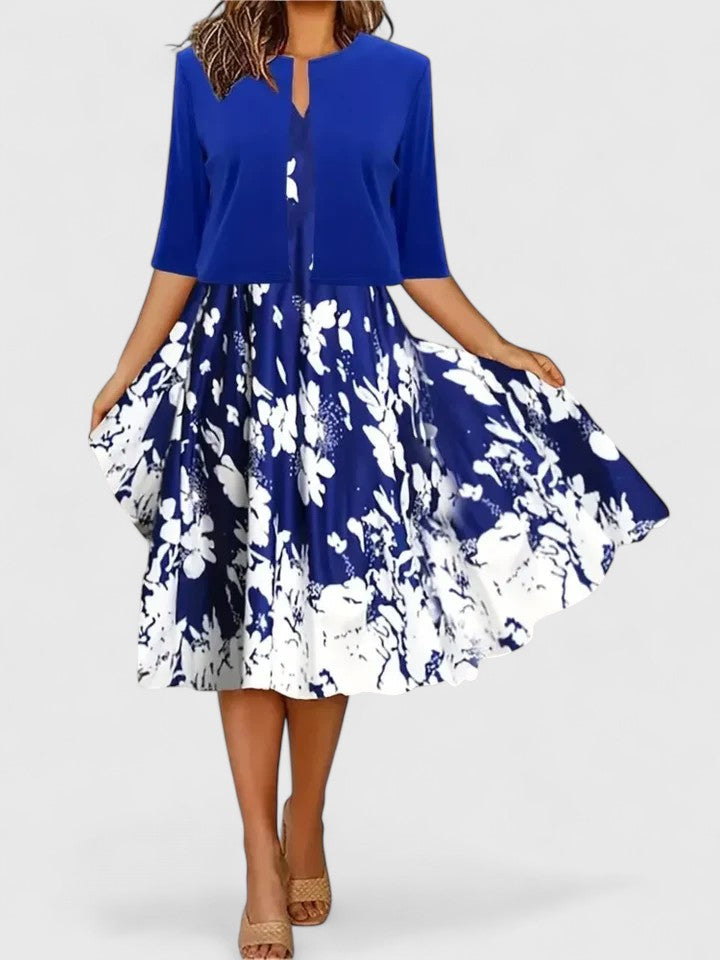 Blue Emma & Rose Cape Town Chantal™ elegant midi dress displayed on a hanger with intricate detailing and flowing fabric.
