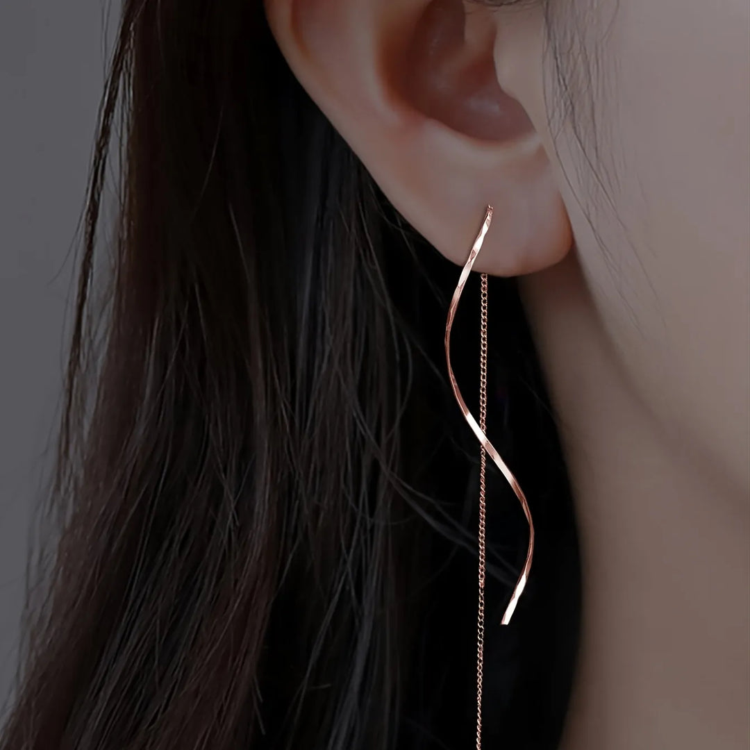Gold Phaedra™ long earrings with wavy design by Emma & Rose Cape Town, featuring elegant, flowing metal curves.