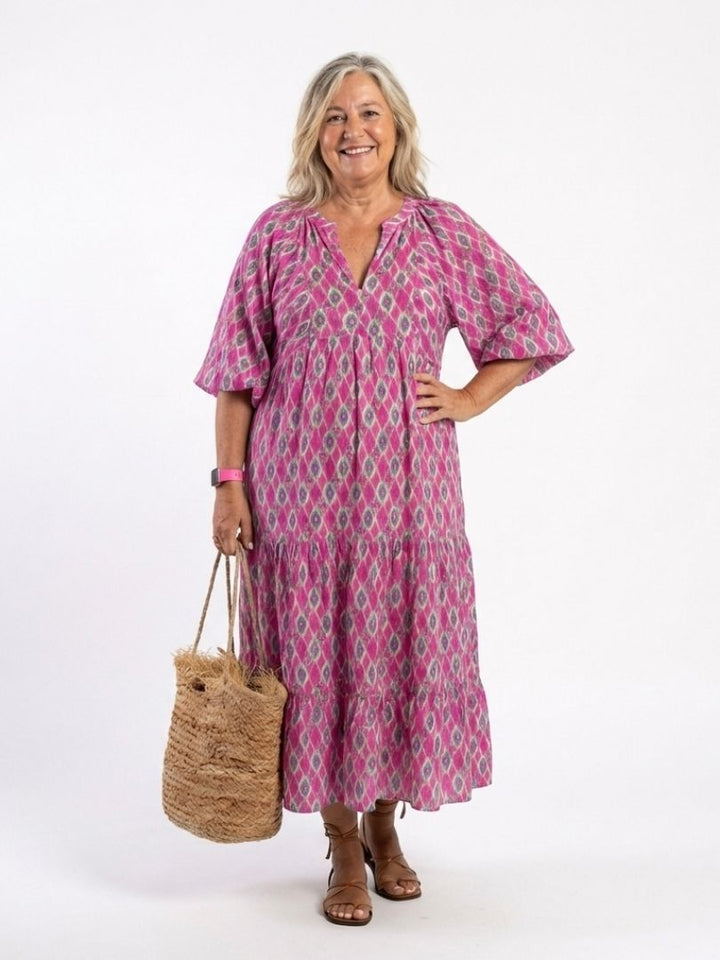 A woman wearing the Emma & Rose Cape Town Apolline™ neck patterned midi dress in green, showcasing its stylish design and fit.