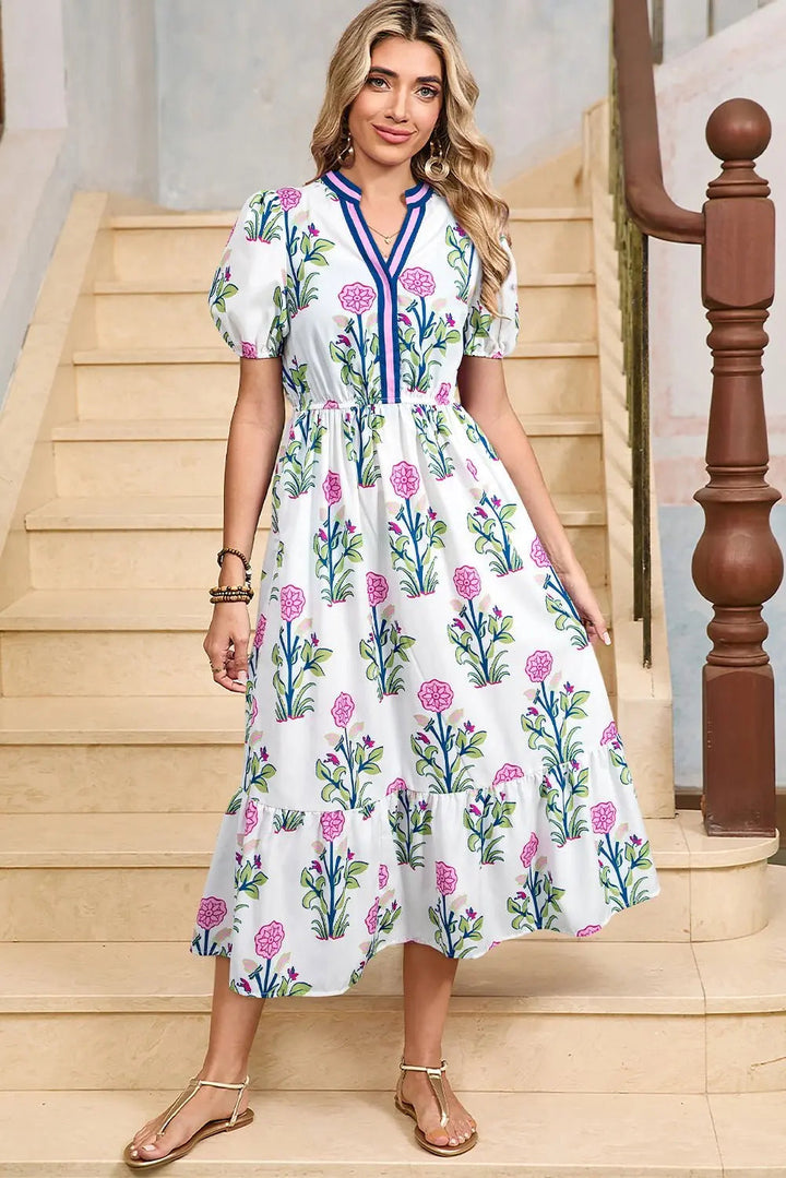 White floral midi dress by Emma & Rose Cape Town with ruffle hem and colorful neckline, perfect for spring and summer occasions.