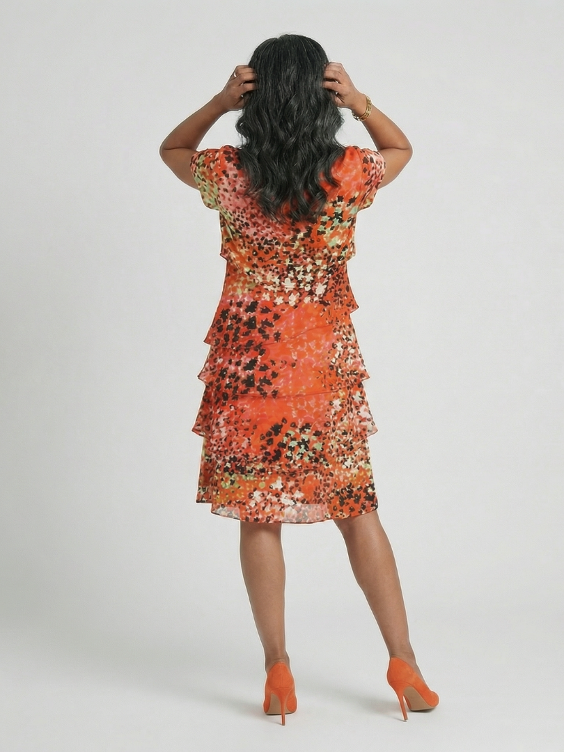 Evania™ tier knee-length dress by Emma & Rose Cape Town in vibrant orange fabric, styled with a flowing silhouette and tiered design.