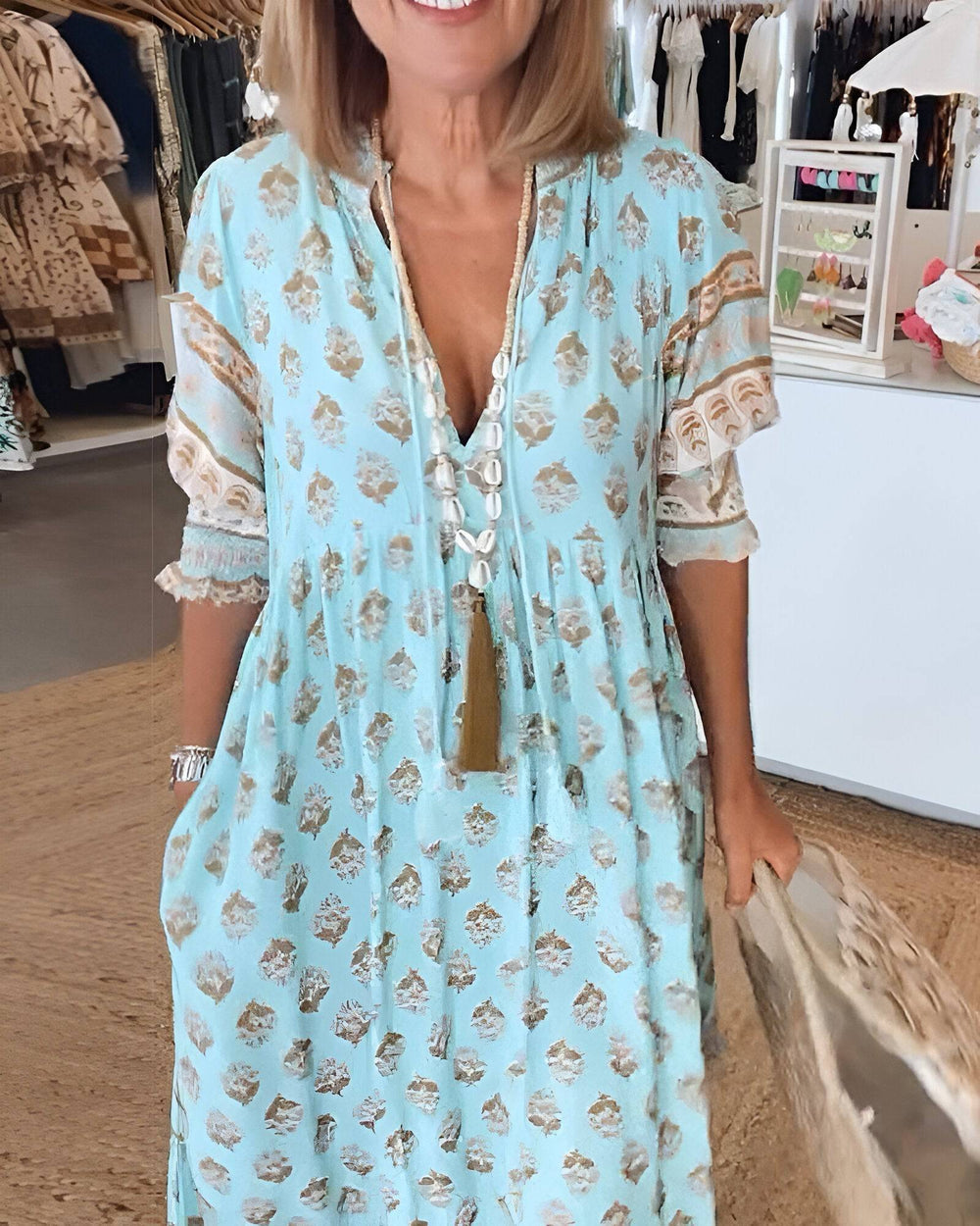 Bérénice™ bright summer dress by Emma & Rose Manhattan with floral pattern and flowing fabric, worn by a model outdoors.
